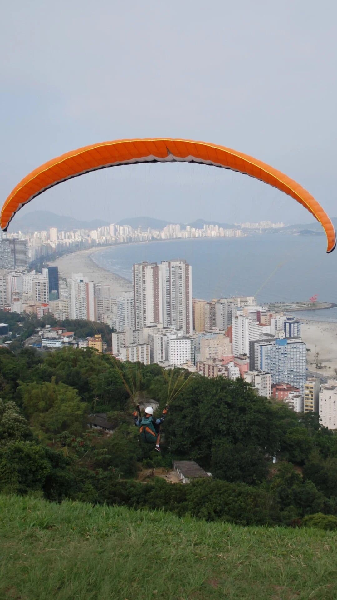 Parapente laranja sobre a orla de Santos e São Vicente